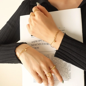 Minimalist double layer gold chain bracelet and rings set shown on a model hand
