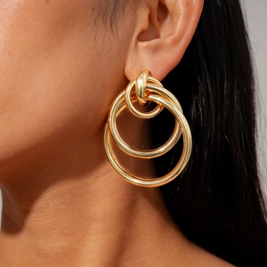 Macro view of gold multi-layer geometric hoop earrings on model showing metal texture