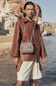 Close-up of beige genuine leather handbag with soft pebble texture and elegant curves