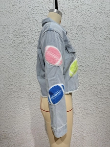 Detail of pink and green chenille football patches on light blue denim jacket sleeve