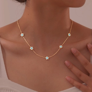 Detailed view of a gold collar chain with five blue and white evil eye flower charms