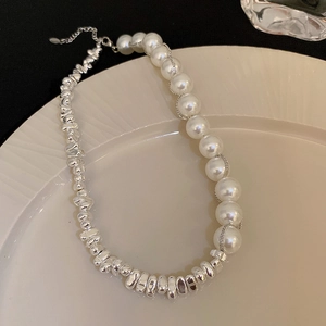 Detail of a half silver metallic beads and half white imitation pearl necklace on a plate