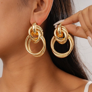 Close-up of a model wearing gold multi-layered geometric hoop earrings in a minimalist style