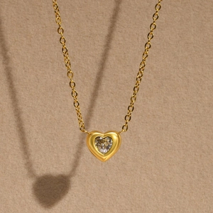 Detailed view of an 18K gold stainless steel heart pendant with a prong-set clear zircon