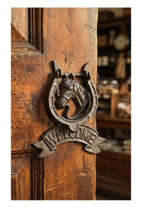 Detail eines antiken Türklopfers aus Gusseisen mit Pferdekopf und Welcome-Schild