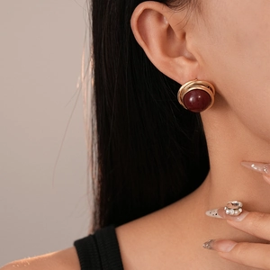 Gros plan de boucles d'oreilles vintage perle rouge et fil d'or torsadé sur le mannequin