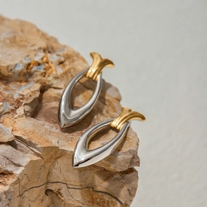 Two-tone geometric stainless steel earrings in silver and gold on a natural stone base