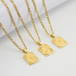 Close-up of gold 18K stainless steel Figaro chains with square K, J, and M letter pendants