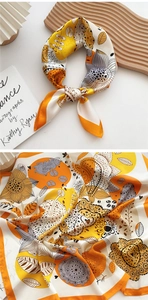 Detail of silk square scarf with orange floral patterns on a wooden tray with a book