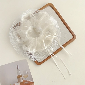 Detail of white lace organza scrunchie with elegant long ribbon on a wooden tray