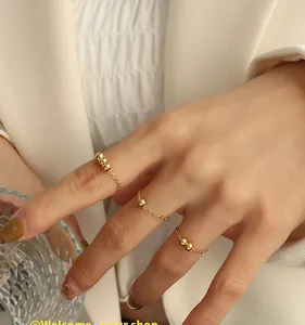 Detaillierte Nahaufnahme eines dreiteiligen goldenen Perlenketten-Ring-Sets am Finger