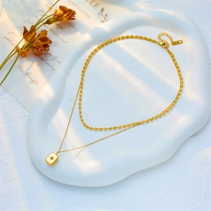 Elegant gold double-layered necklace featuring a star rectangular pendant on ceramic tray
