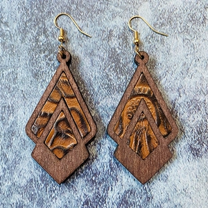Detailed view of geometric diamond earrings made of brown leather and wood on blue background