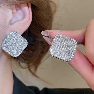 Primo piano di orecchini a lobo quadrati in argento con cristalli scintillanti sul modello