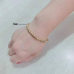 Detailed view of golden stainless steel beaded bracelet featuring 5mm spheres on wrist