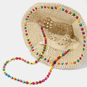 Détail d'un chapeau de paille beige avec perles en bois colorées et lanière perlée