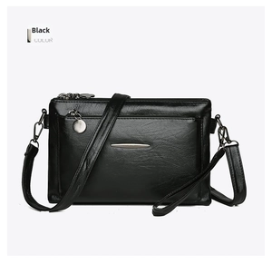 Close-up of black crossbody bag with soft faux leather texture and metallic zippers