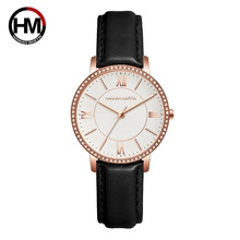 Detail of Hannah Martin rose gold watch featuring a white dial and black leather strap