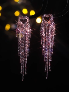 Close-up of luxury long tassel earrings with pink rhinestones and heart-shaped design