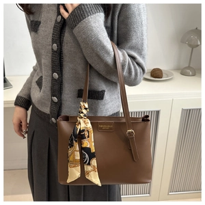 Detail der dunkelbraunen Leder-Shopper mit bedrucktem Seidenschal an einem Modell