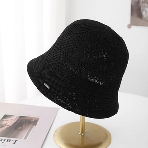 Minimalist black knitted bucket hat with JSHAT metal logo on a stylish display stand