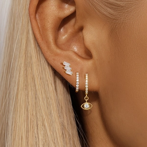 Detail of gold S925 silver ear set featuring evil eye charm and sparkling zircon studs