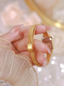 Detailed close-up of a luxury gold mesh strap and secure clasp on a lady's square watch