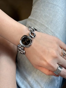 Close-up of a stylish silver irregular hollow bracelet watch with a dark dial on a wrist
