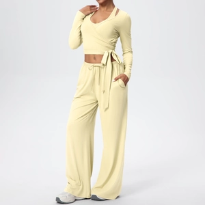Détail d'ensemble de yoga jaune avec haut cache-cœur, nœud latéral et pantalon large