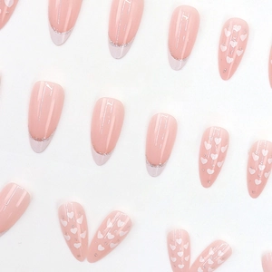 Pink almond press-on nails with white heart patterns and silver glitter French tips