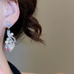 Macro shot of long drop earrings with heart crystals and sparkling flower ribbon details