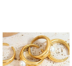 Detailed macro view of gold-plated rings with white pearls on a natural stone base