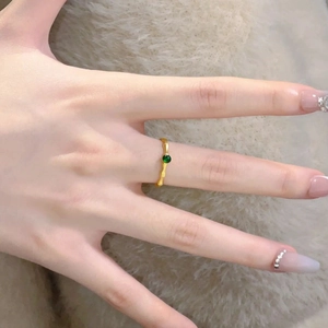 New Chinese style gold bamboo ring with green jadeite stone on a plush background
