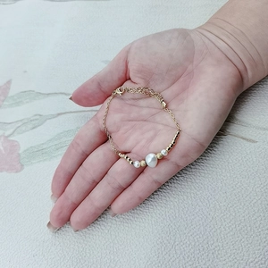 Detail of a gold stainless steel bracelet with a large baroque pearl and lobster clasp