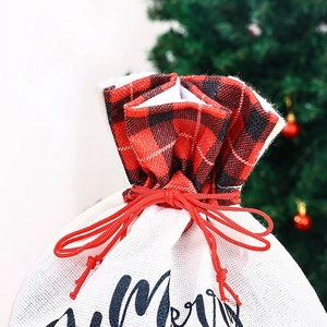 Close-up of burlap Christmas gift bag with red plaid drawstring and Merry text