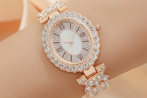 Detail of rose gold diamond watch on wrist with elegant sparkling metal strap