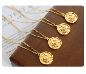 Macro view of four vintage gold necklaces featuring celestial sun, moon, and star pendants