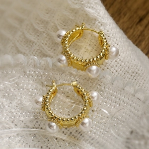 Vintage gold plated pearl hoop earrings with granulated texture on a lace background