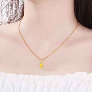 Close-up of a gold necklace featuring a yellow chili pepper enamel pendant on a neck