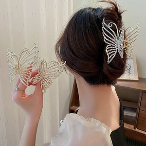 Elegant gold butterfly hair claw clips with rhinestones and pearls on a sleek hairstyle