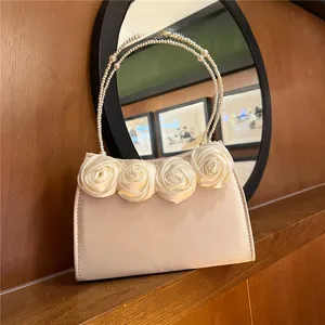 Detail of satin evening bag with decorative fabric roses and pearl beaded handle