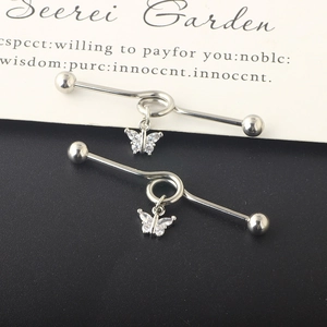 Macro shot of silver barbell piercing with butterfly pendant and inset sparkling stones
