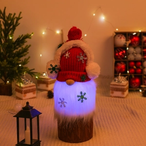 Luminous Christmas gnome decoration with knitted hat and glowing beard on wooden base