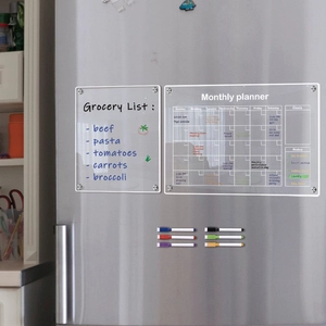 Macro view of magnetic acrylic grocery list and monthly planner on a grey fridge