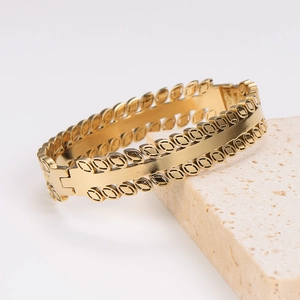 Vintage gold stainless steel bangle with leaf pattern displayed on a light stone base