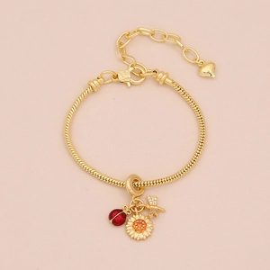 Détail du bracelet chaîne serpent doré avec breloques coccinelle, tournesol et libellule