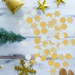 Festive gold and silver snowflake confetti with round sequins on white wooden background
