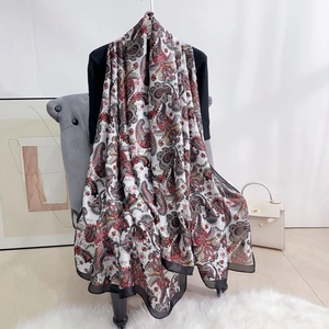 Detail of colorful paisley print scarf with black trim draped elegantly over a chair