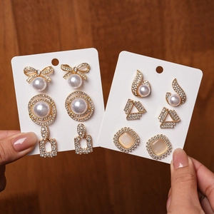 Close-up of golden earring set with pearls, rhinestones, and opal on a display card