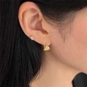 Close-up of golden twisted spiral earrings and sparkling stud set on model